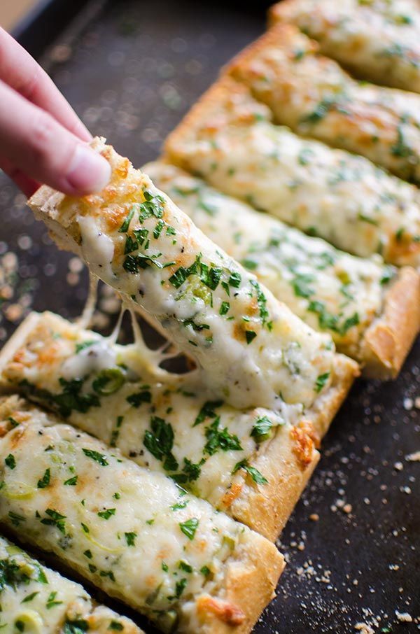 someone is taking a slice of pizza with cheese and parsley on it, along with other slices