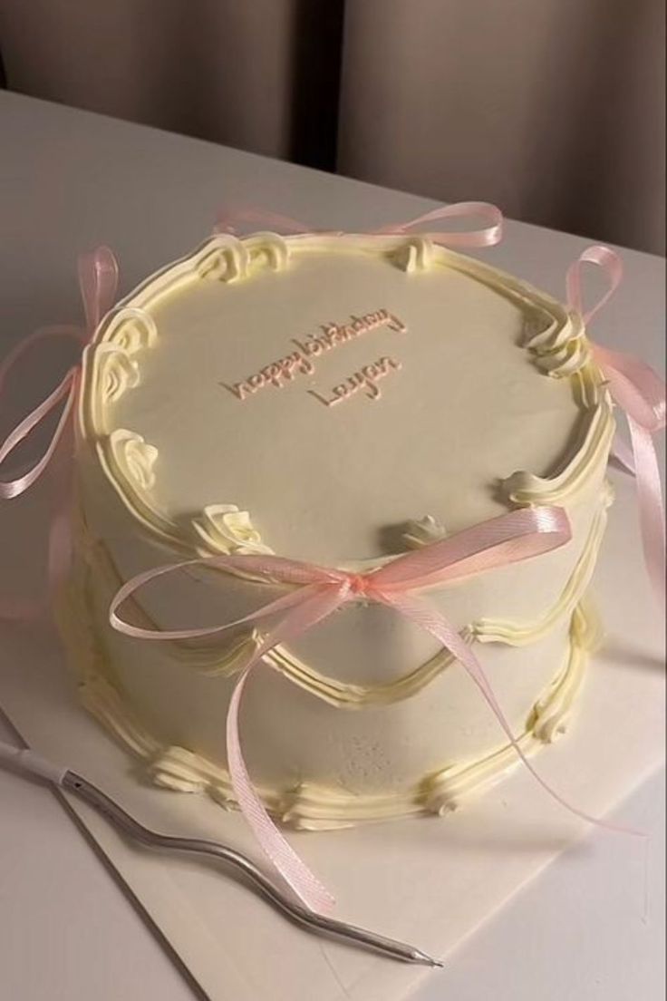 a white cake with pink ribbon and congratulations written on it, sitting on a table