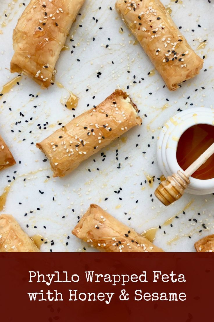 some food that is laying out on a table with honey and sesame seeds next to it