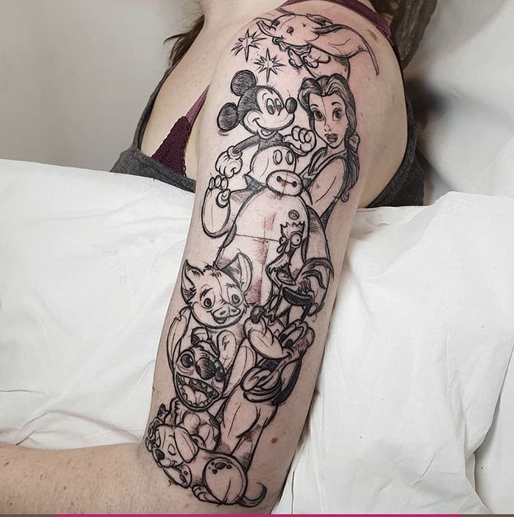 a woman laying in bed with a tattoo on her arm that has an image of mickey mouse and pluto