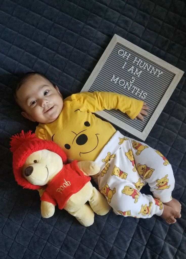 a baby laying on top of a bed next to two stuffed animals