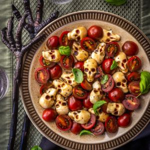 a plate filled with tomatoes and skulls on top of a table next to utensils