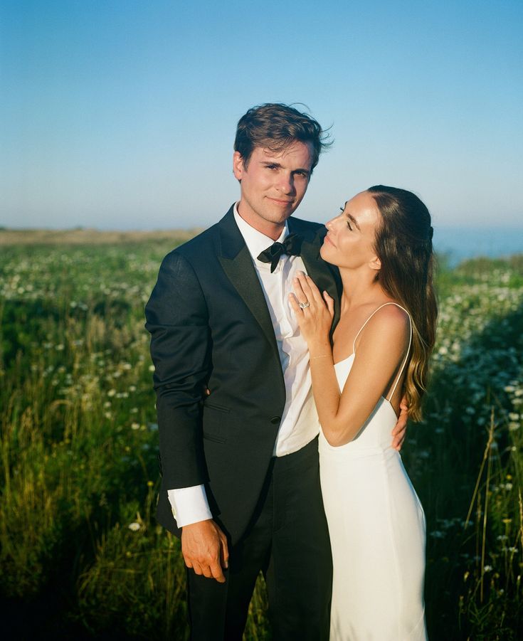 a man in a tuxedo standing next to a woman wearing a white dress