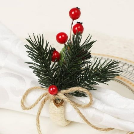 a small pine branch with red berries tied to it on a white table cloth next to a plate