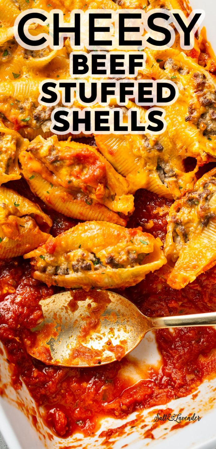 cheesy beef stuffed shells in a white casserole dish with a spoon