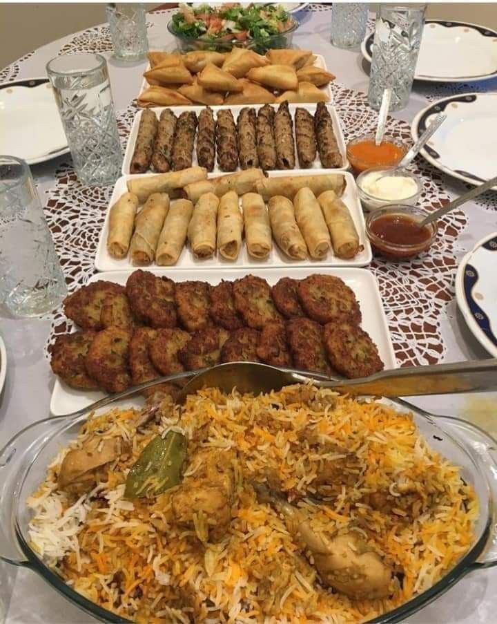 a table filled with plates and trays of food on top of each other,