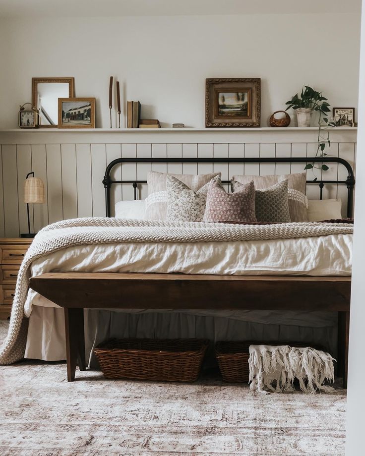 a bed with white sheets and pillows in a bedroom next to a wooden shelf filled with pictures