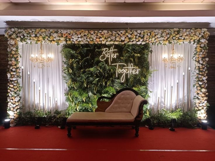 a couch sitting on top of a red carpet next to a wall covered in greenery