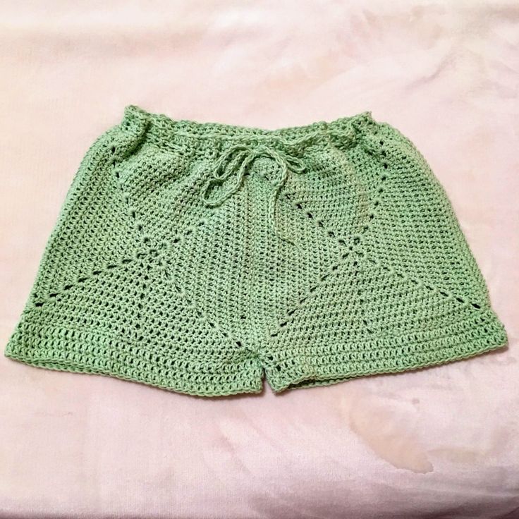 a green crocheted shorts is laying on a bed