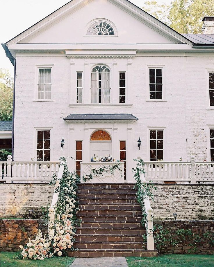 a white house with steps leading up to it and flowers growing on the front door