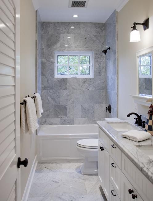 a white bathroom with marble counter tops and walls, along with a walk in shower