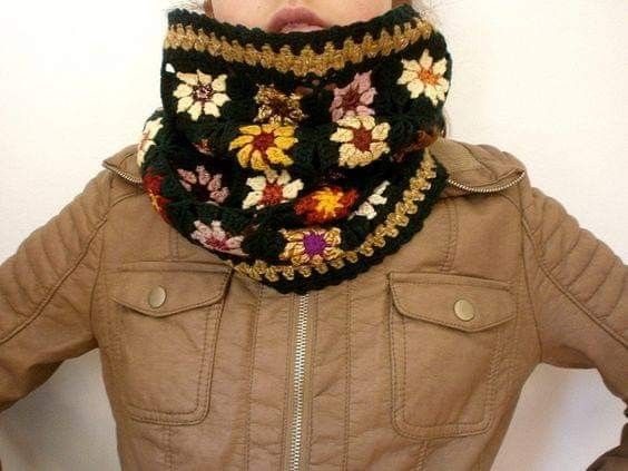 a woman wearing a crocheted scarf with flowers on it