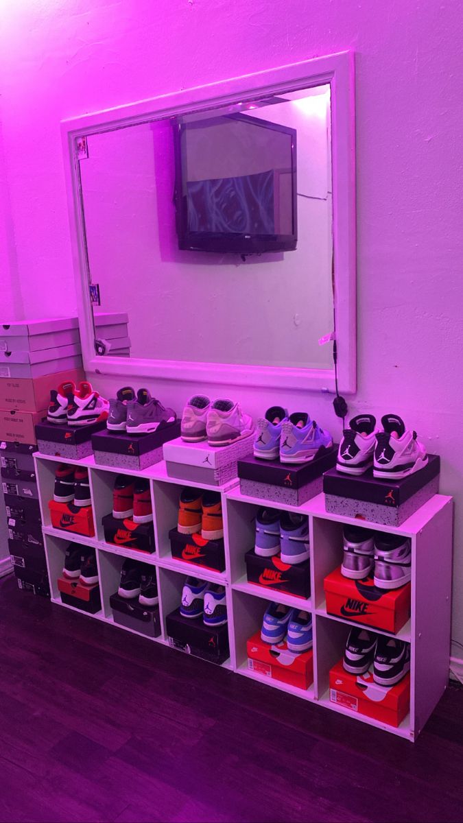 there are many pairs of shoes sitting on the shelf in front of the mirror that is lit up