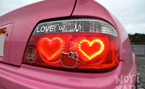 a pink car with two hearts painted on it's tail lights and hello kitty stickers