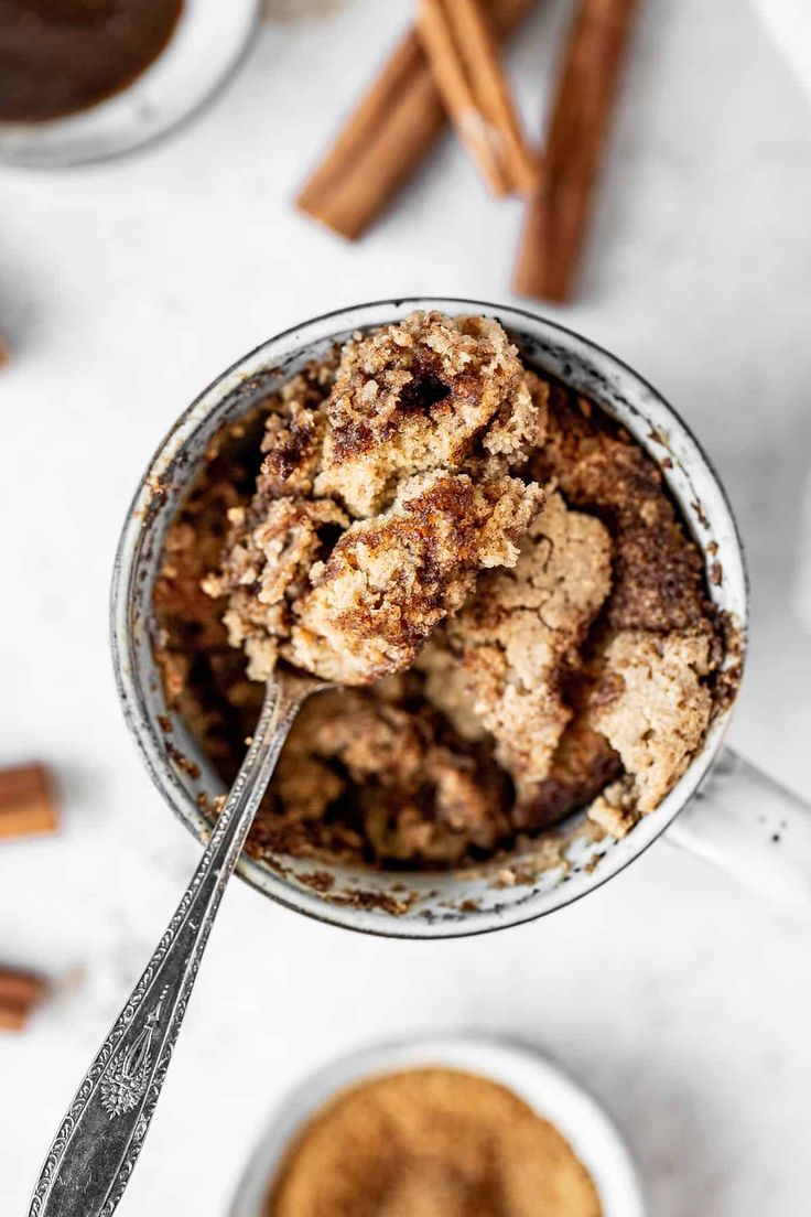 a bowl filled with dessert next to cinnamon sticks