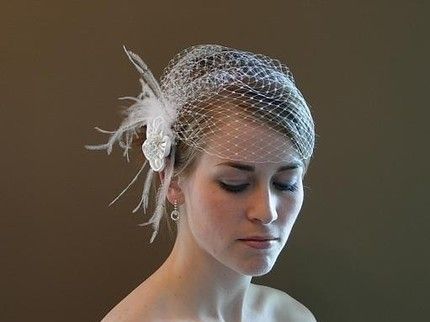 a woman wearing a veil with feathers on her head