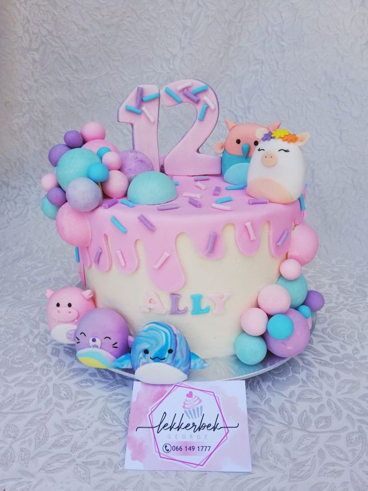 a birthday cake decorated with fondant and pastel decorations, is displayed on a table