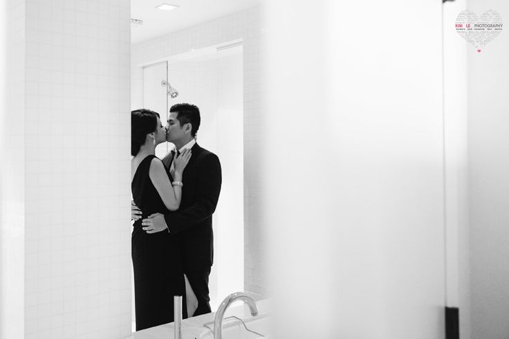 a man and woman standing in front of a bathroom mirror kissing on the foreheads