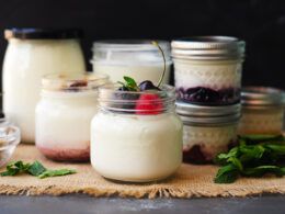 jars filled with yogurt and berries on top of a burlly cloth