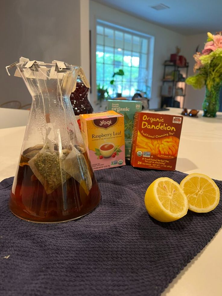 a pitcher filled with liquid sitting on top of a table next to some lemons