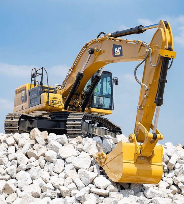 an excavator sits on top of a pile of rocks