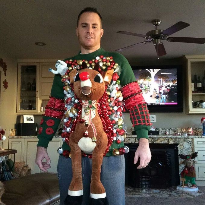 a man in a christmas sweater holding a reindeer