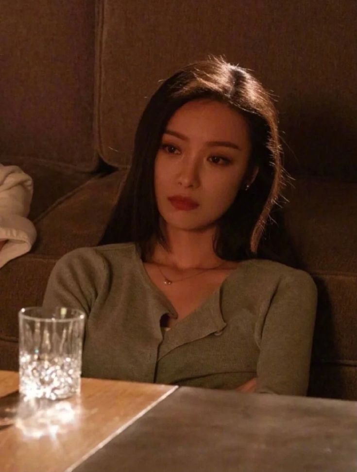 a woman sitting at a table with a glass in front of her on the couch