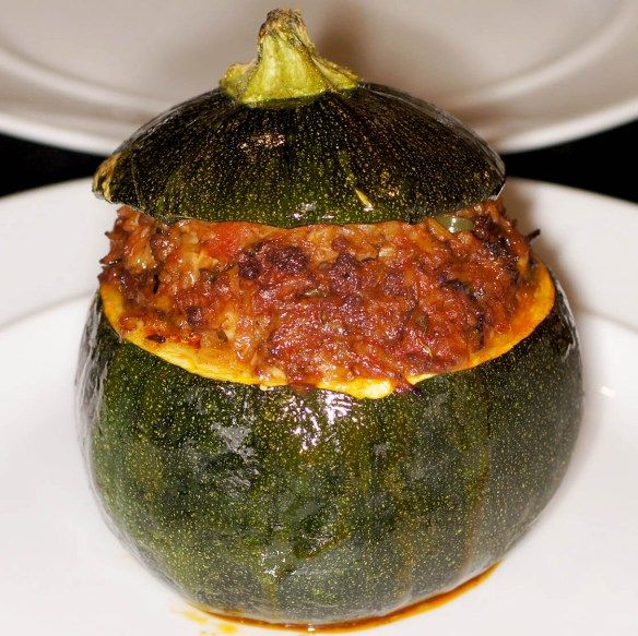 a stuffed zucchini sitting on top of a white plate with sauce in it