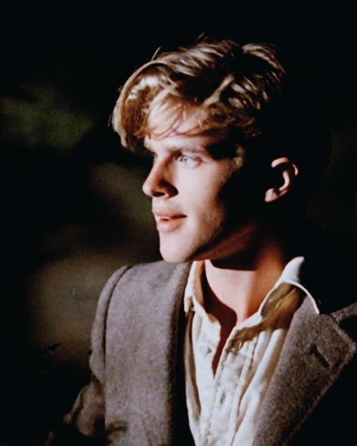 a man with blonde hair wearing a suit and white shirt looking off into the distance