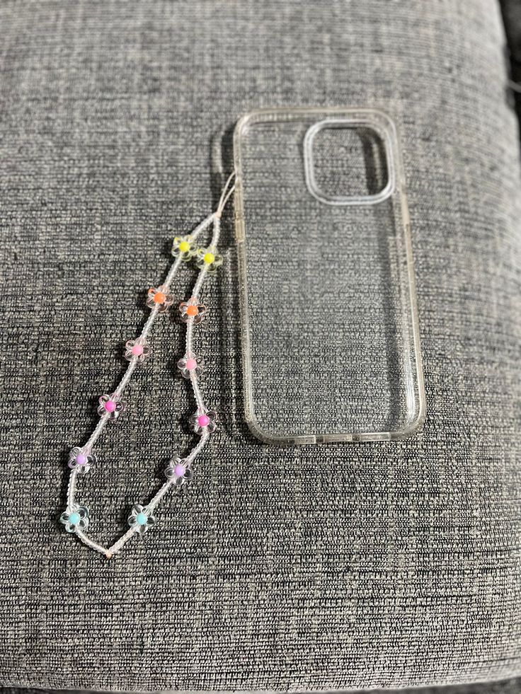 a cell phone case sitting on top of a gray couch next to a string of beads