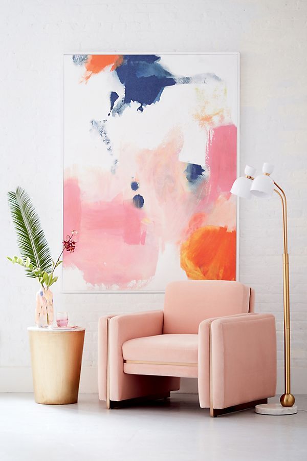 a pink chair sitting next to a potted plant in front of a large painting