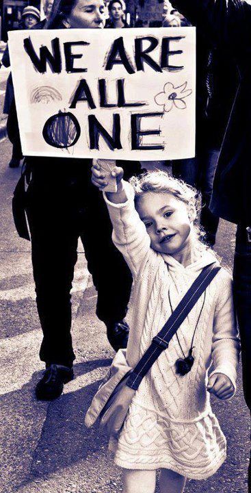 a woman holding up a sign that says we are all one