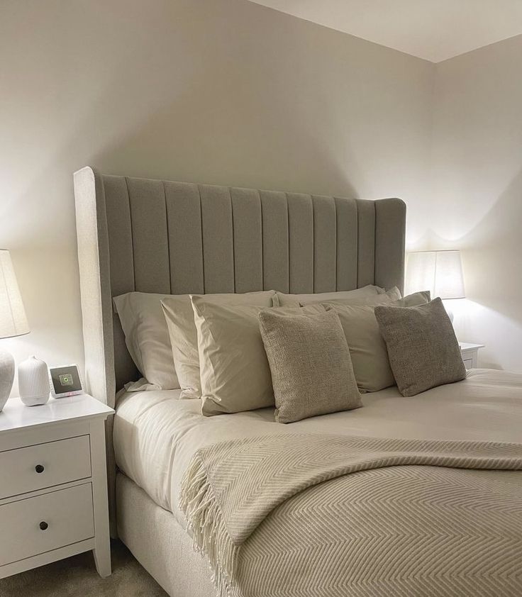 a bed with white linens and pillows in a small room next to two nightstands