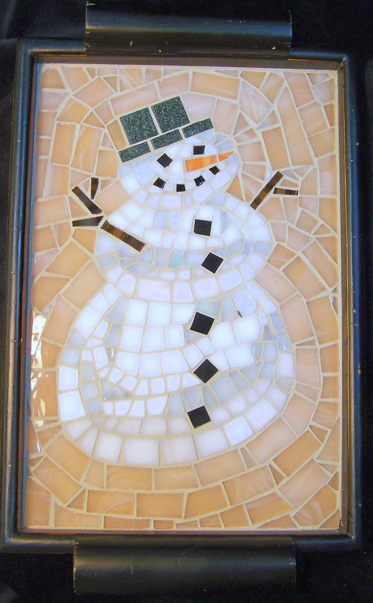 a snowman made out of small pieces of glass and mosaic tiles on a black frame