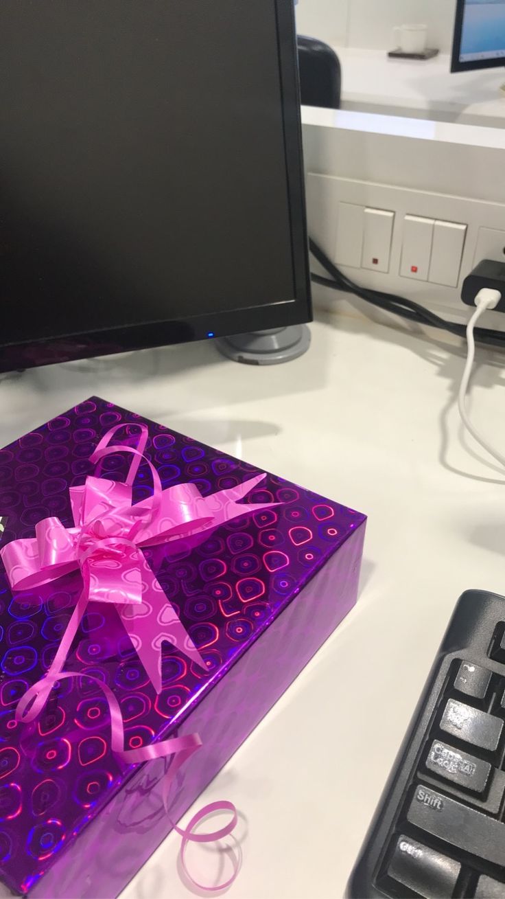 a purple gift box sitting on top of a computer desk