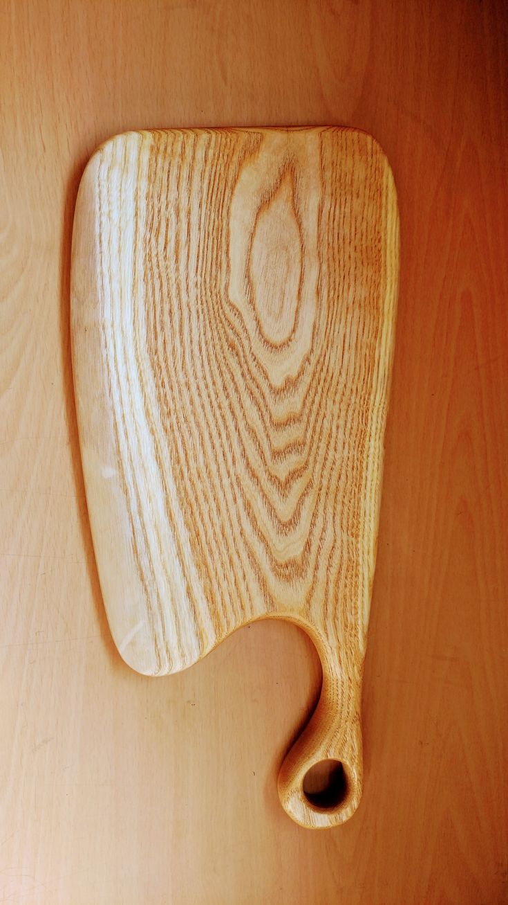 a wooden cutting board sitting on top of a table next to a knife holder with a hole in it