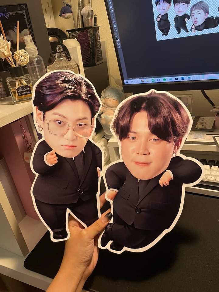 two people holding up cutouts of themselves in front of a computer