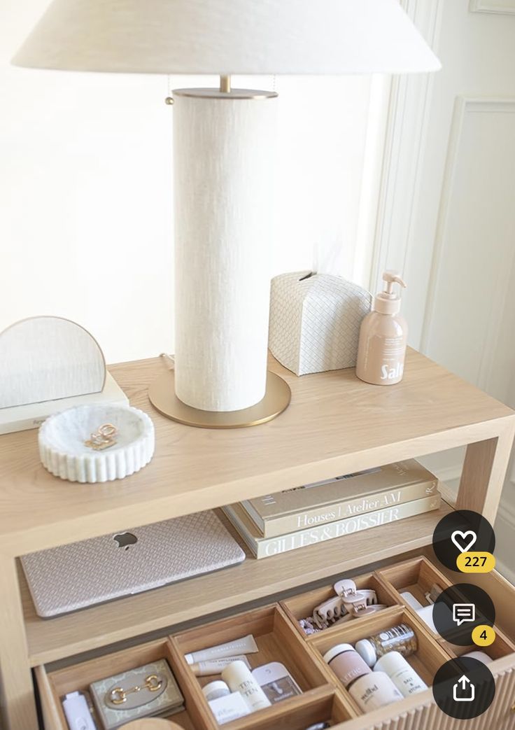 an open drawer on a table next to a lamp and other items that are in it