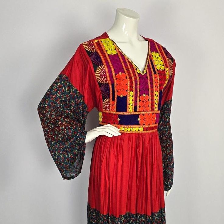 This dress expertly blends traditional Afghan patterns with contemporary style.  Crafted from high-quality cotton, the airy and lightweight fabric makes it ideal for summer wear.  The chest part of the dress is entirely decorated and covered by embroidered borders. The sleeves and the bottom hem of the dress are set with accents of recycled fabrics in floral print. The waist can be adjusted using the attached ribbons, ensuring a flawless fit. For your comfort, this dress has a zipper on the back Traditional Flowy Embroidered Dresses, Traditional Embroidered Flowy Dress, Traditional Flowy Boho Dress For Spring, Flowy Boho Dress For Spring, Folk Style Festive Dress With Chikankari Embroidery, Multicolor Cotton Embroidered Dress For Festivals, V-neck Dresses With Chikankari Embroidery For Festivals, Cotton Embroidered Dress With Resham Embroidery For Festival, Flowy Boho Summer Dress