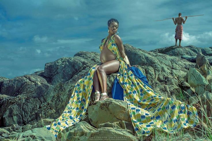 a woman sitting on top of a rock next to a man with a stick in his hand