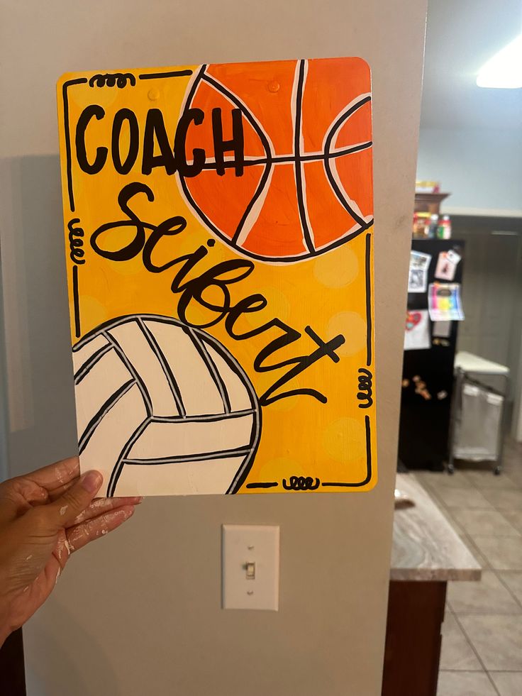 a person holding up a sign with a volleyball on it that says coach seriey