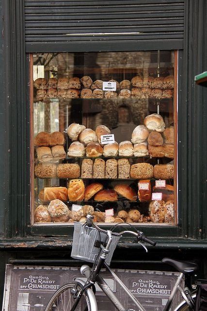 a bicycle parked in front of a store window filled with breads and pastries