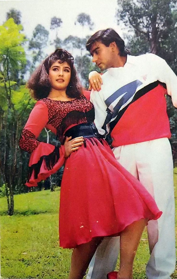 a man and woman dressed in costume posing for a photo on the grass with trees in the background