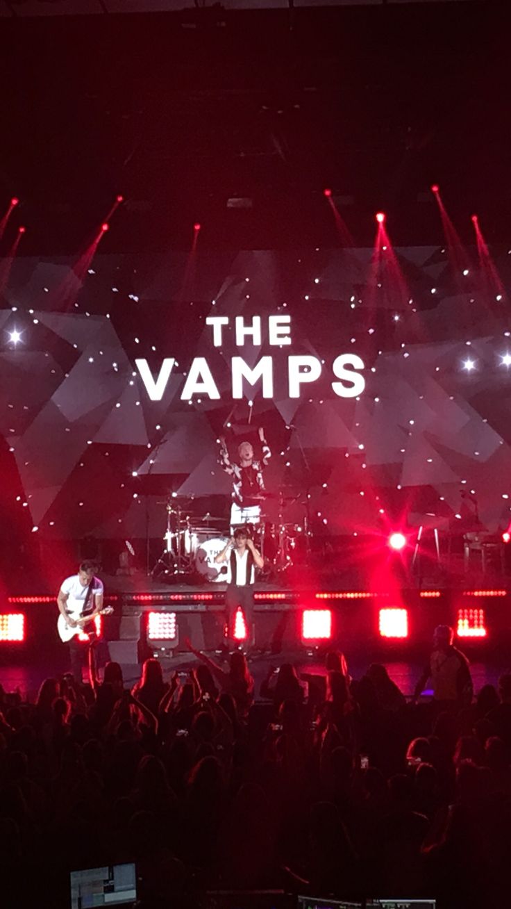 the vampires performing on stage with red and white lights in the background at an event