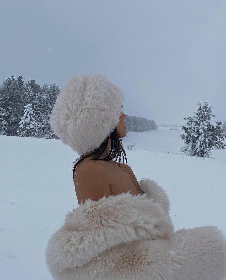 a woman wearing a white fur coat in the snow