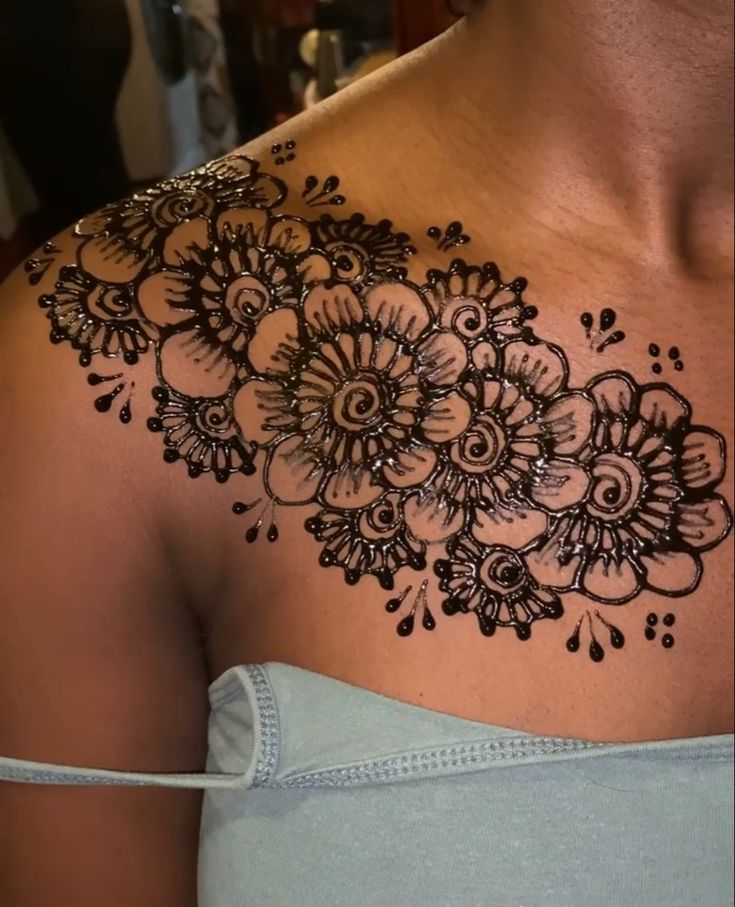 a woman's shoulder with black and white flowers on it, in the middle of her chest