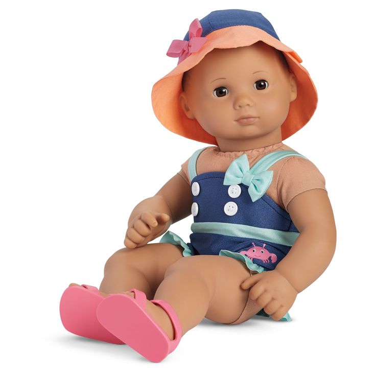 a baby doll sitting on the ground wearing a hat