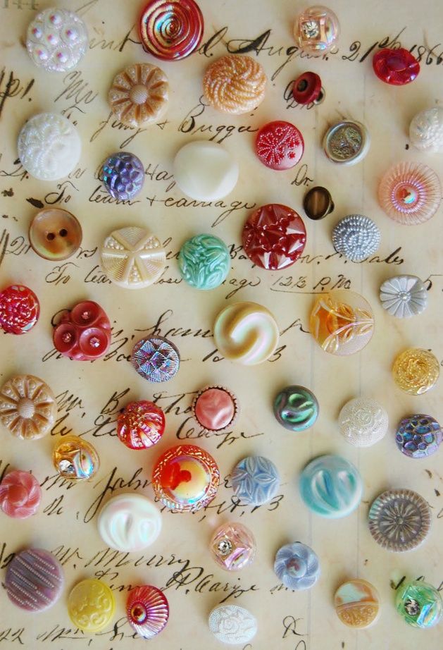 many different colored buttons on a sheet of paper next to an old handwritten letter