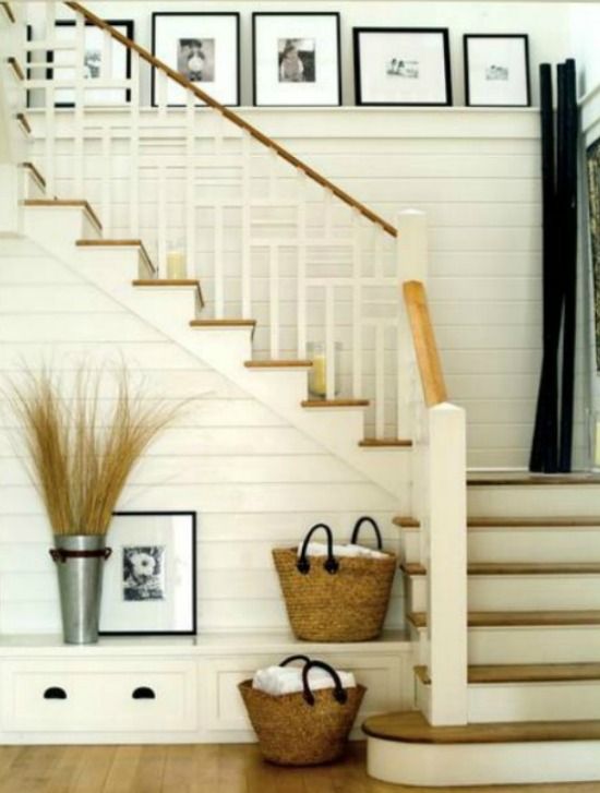 two baskets on the floor in front of stairs with pictures on the wall behind them