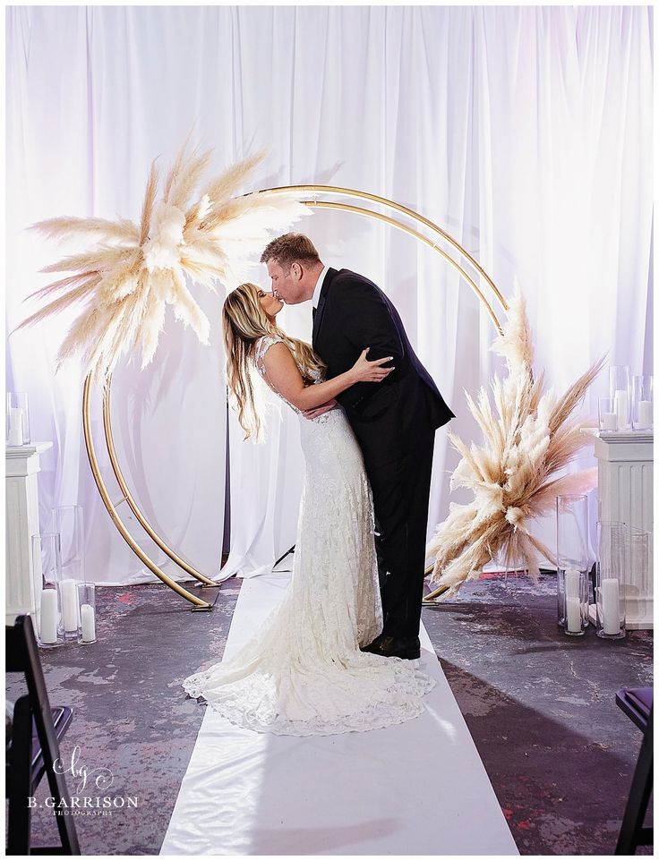 a bride and groom kissing in front of a backdrop